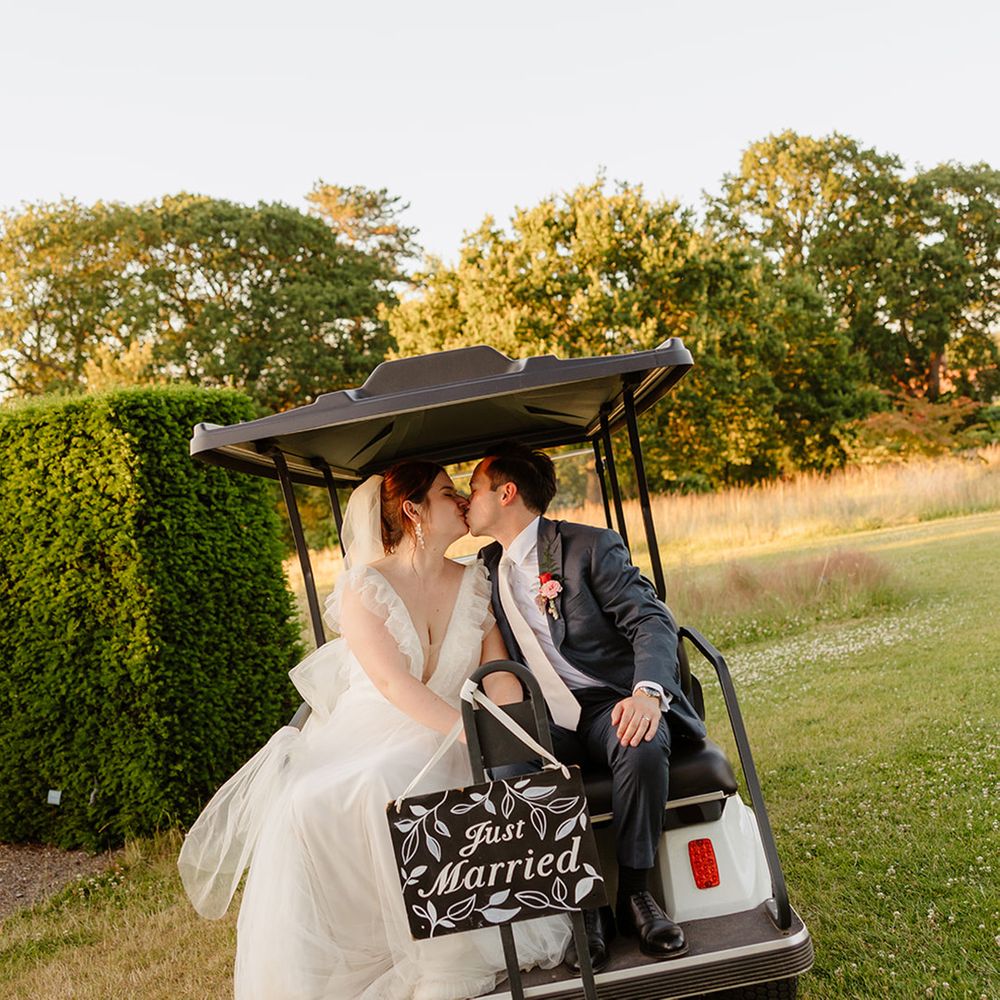 bride-and-groom-riding-on-golf-cart-with-just-married-sign