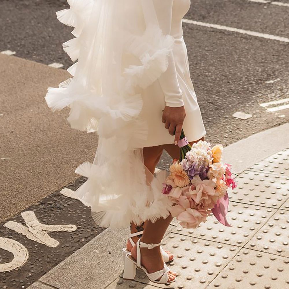Stylish and chic bride wearing an off the shoulder long sleeve short hen party dress idea paired with a ruffle veil