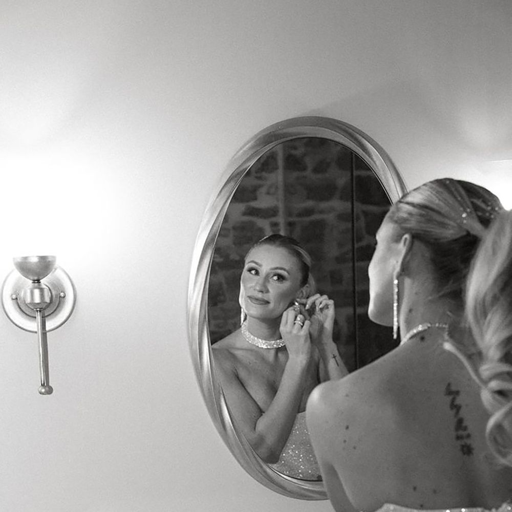 Bride in strapless sequin hen party dress idea with hair in blonde ponytail looking in the mirror