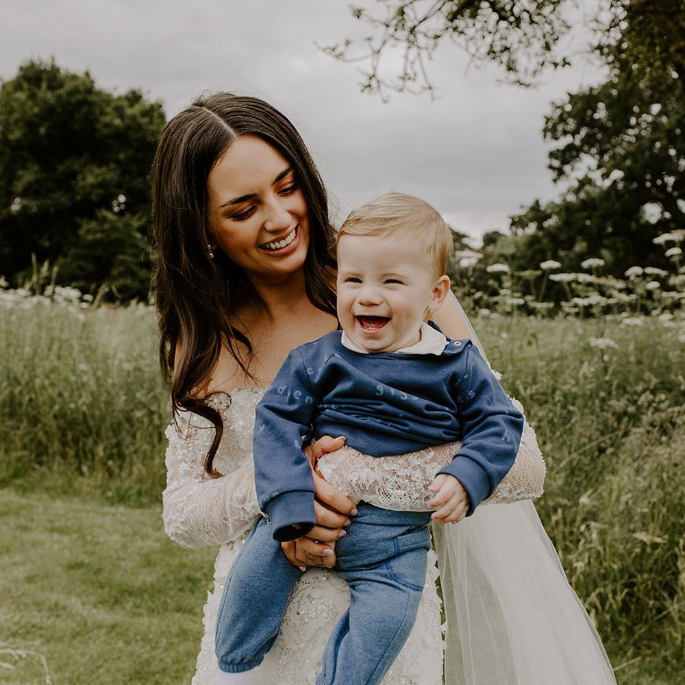 bride-carrying-baby-boy-in-blue-tracksuit