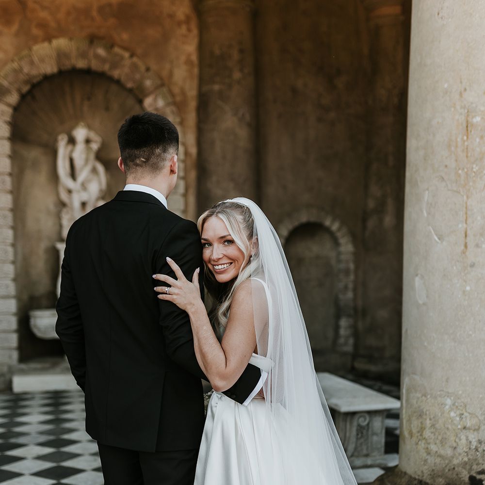 bride-smiles-at-camera-embracing-groom