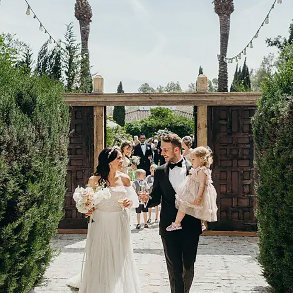 bride-and-groom-walking-with-their-daughter-and-chamapgne-glasses-to-celebrate-wedding