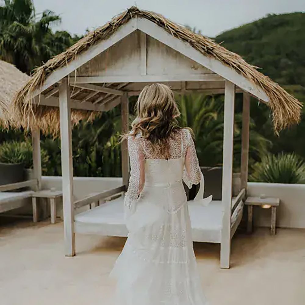 bride-in-a-boho-lace-wedding-dress-with-long-sleeves-walking-by-the-pool-a-pure-house-ibiza-wedding-venue