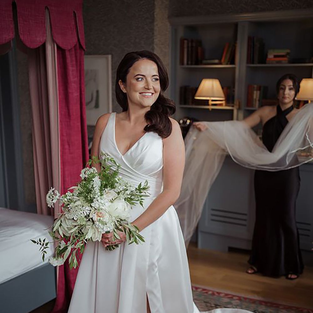 bride wearing classic traditional wedding dress with front slit, while holding bouquet
