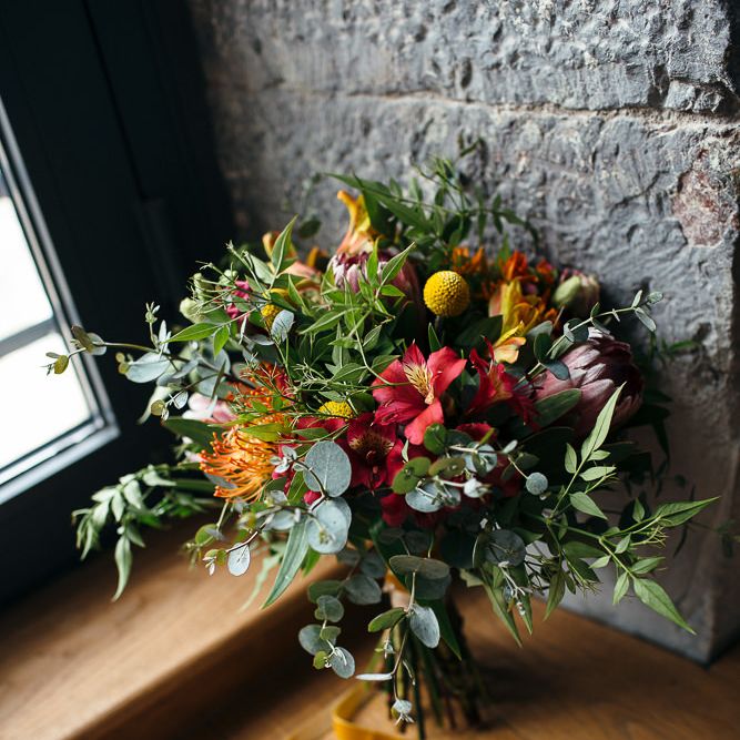 Colourful Red, Orange & Yellow Bouquet with Proteas | Relaxed Industrial Wedding at Ocean Studios, Plymouth | Freckle Photography