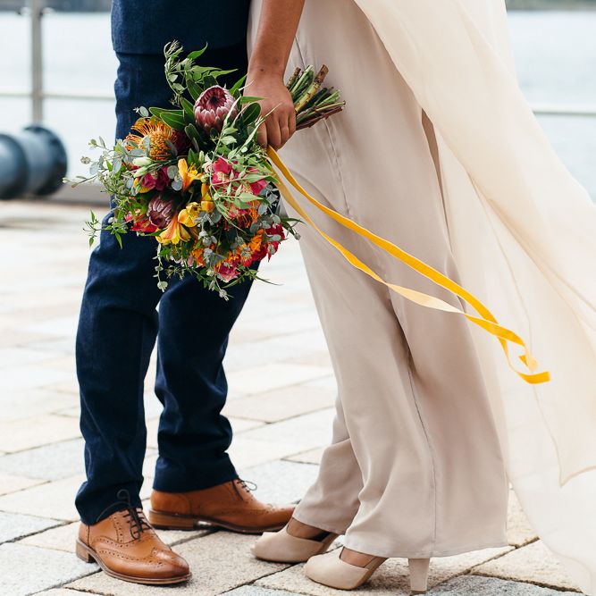 Bride in Bespoke Ailsa Monroe Jumpsuit & Cape | Groom in Next Navy Wool Suit | Relaxed Industrial Wedding at Ocean Studios, Plymouth | Freckle Photography