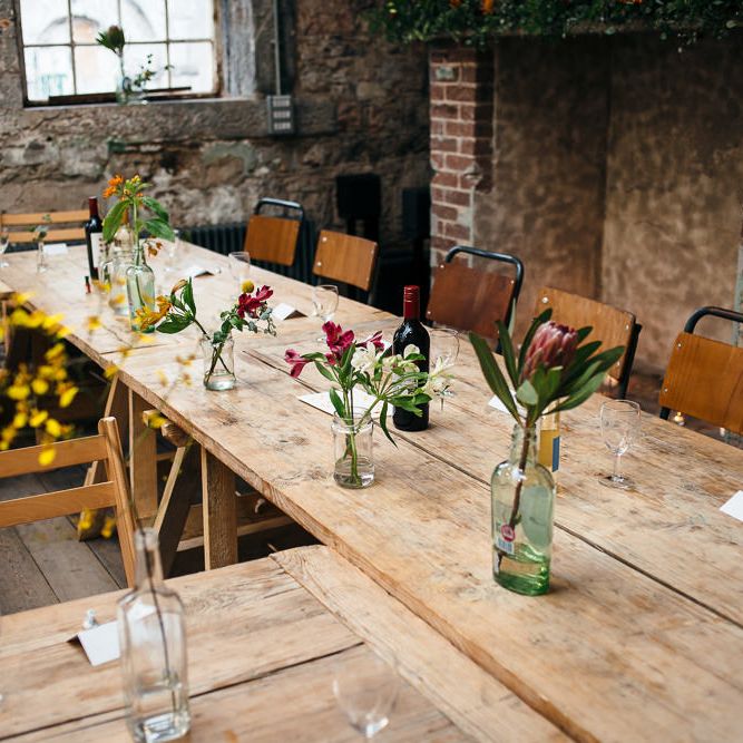 Trestle Tables with Flower Stems in Bottles | | Relaxed Industrial Wedding at Ocean Studios, Plymouth | Freckle Photography