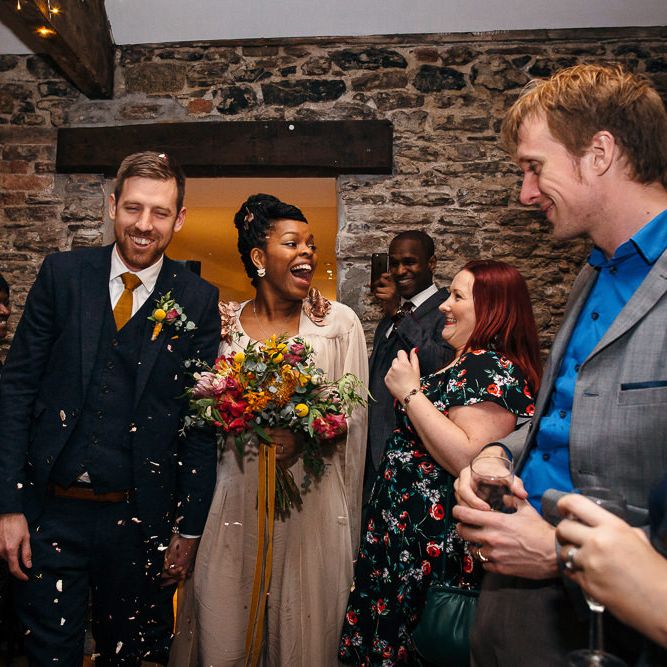 Confetti Exit | Bride in Bespoke Ailsa Monroe Jumpsuit & Cape | Groom in Next Navy Wool Suit | Relaxed Industrial Wedding at Ocean Studios, Plymouth | Freckle Photography