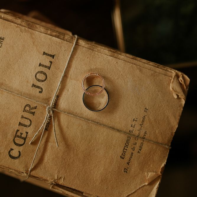 Wedding rings in dark wedding photo propped on old book