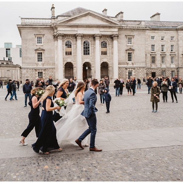 Wedding party walking with bride and groom through plaza