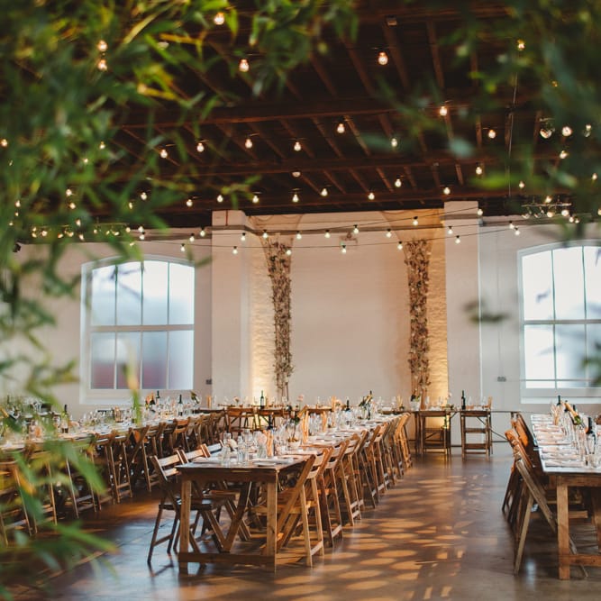 Warehouse Wedding With Wooden Chairs & Foliage Installation | Images by Frances Sales