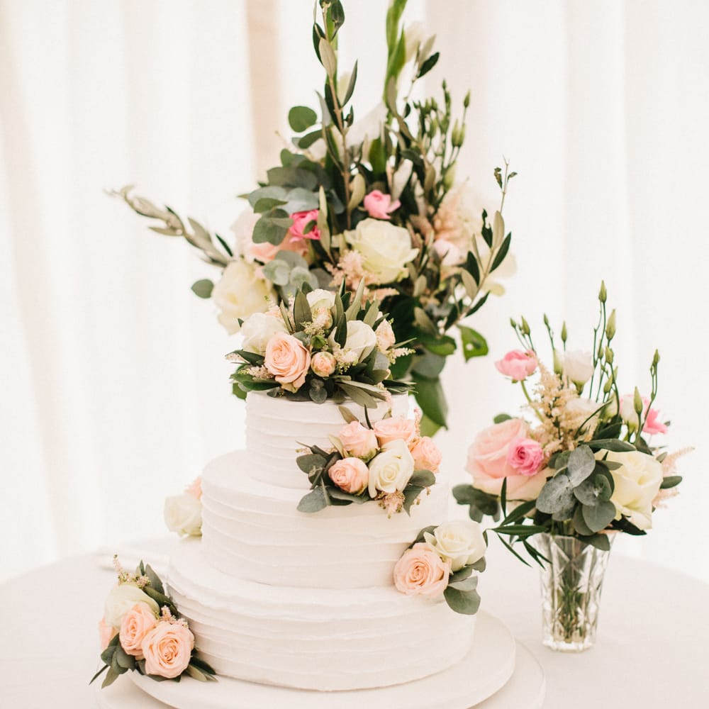 White Wedding Cake Covered In Flowers