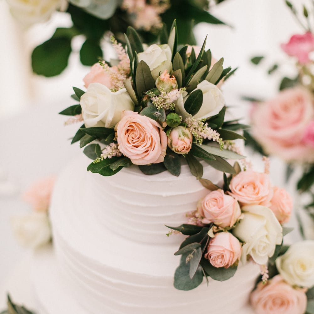 White Wedding Cake Covered In Flowers
