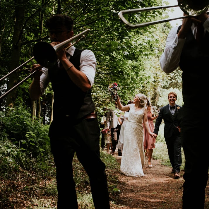 Brass Band Procession | Bride in Catherine Deane Gown | Groom in Ben Sherman Suit, Bow Tie & Gingham Shirt | Colourful Outdoor Wedding at Lineham Farm in Leeds | Shutter Go Click Photography