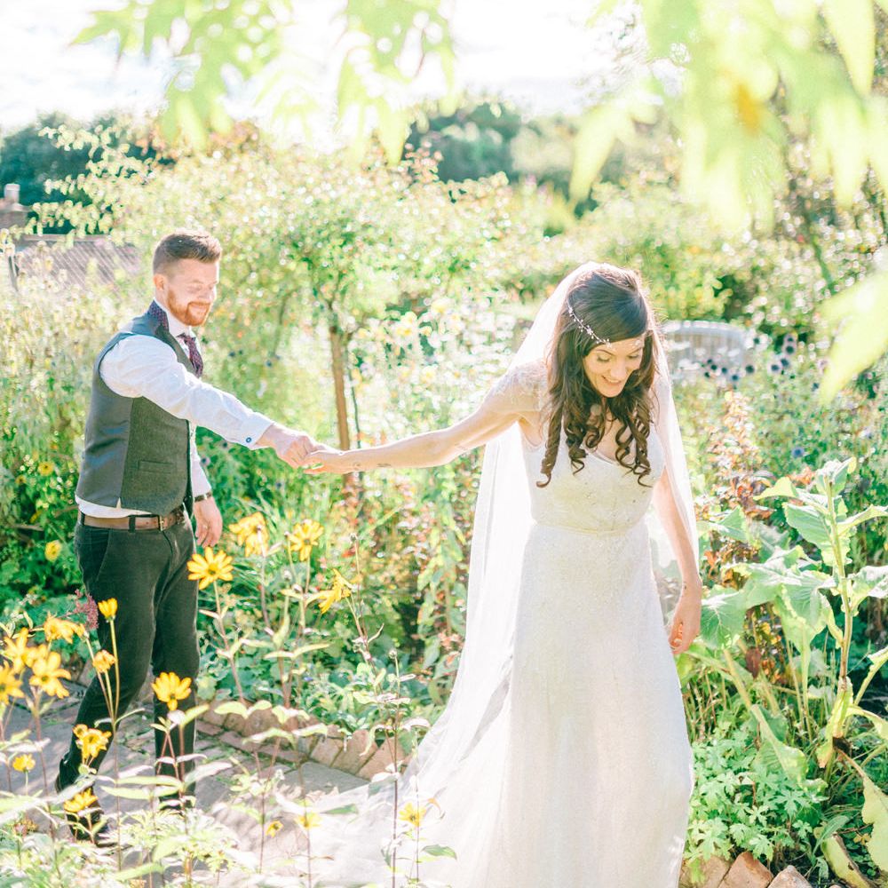 Bride leads groom by the hand through botanical glasshouse