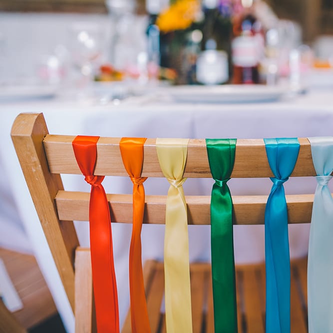 Rainbow Ribbon Details On Chairs For Wedding // Outdoor Summer Wedding With Bright Colour Scheme With Colourful Homemade Decor And Images From Story + Colour Photography