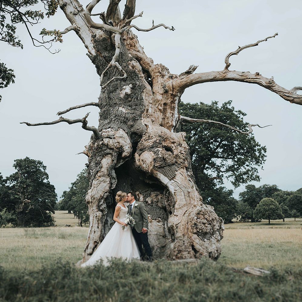 Bride in Phil Collins Bridal Gown & Groom in Chino's & Tweed Jacket at Helmingham Hall Gardens
