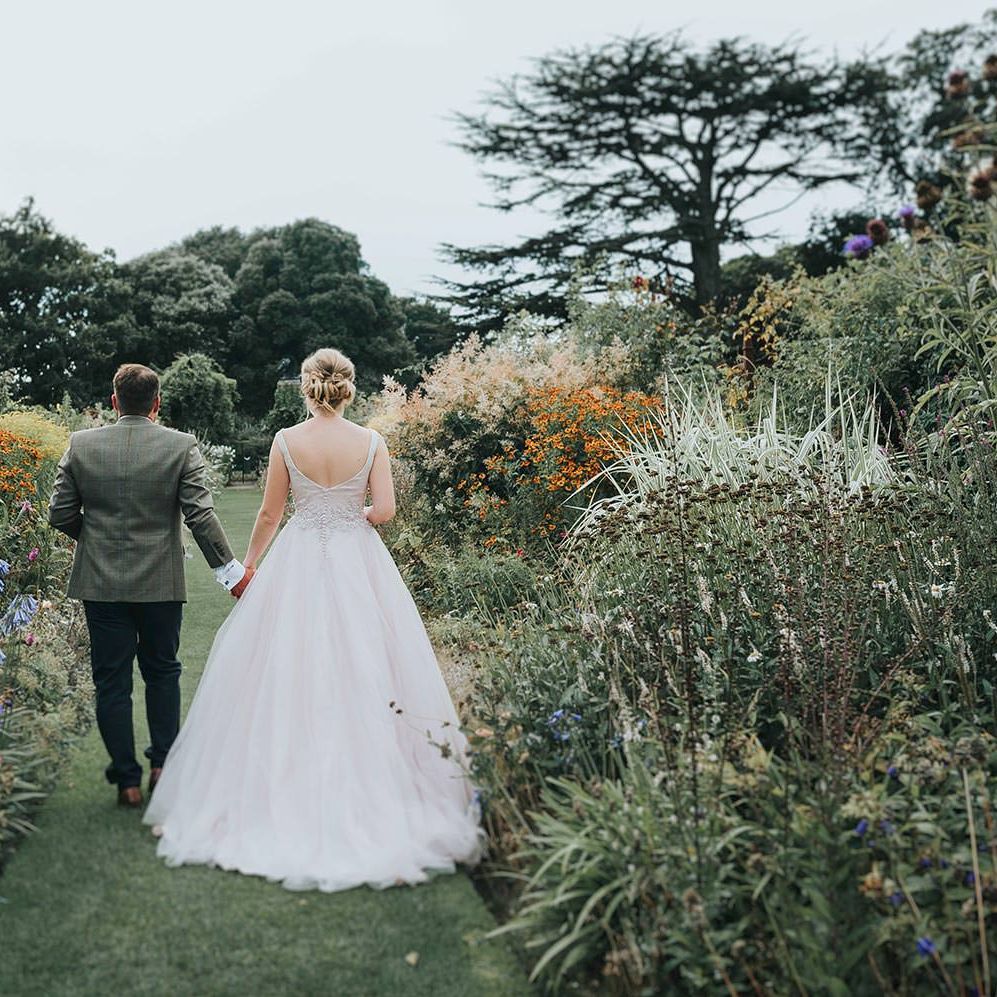 Bride in Phil Collins Bridal Gown & Groom in Chino's & Tweed Jacket at Helmingham Hall Gardens