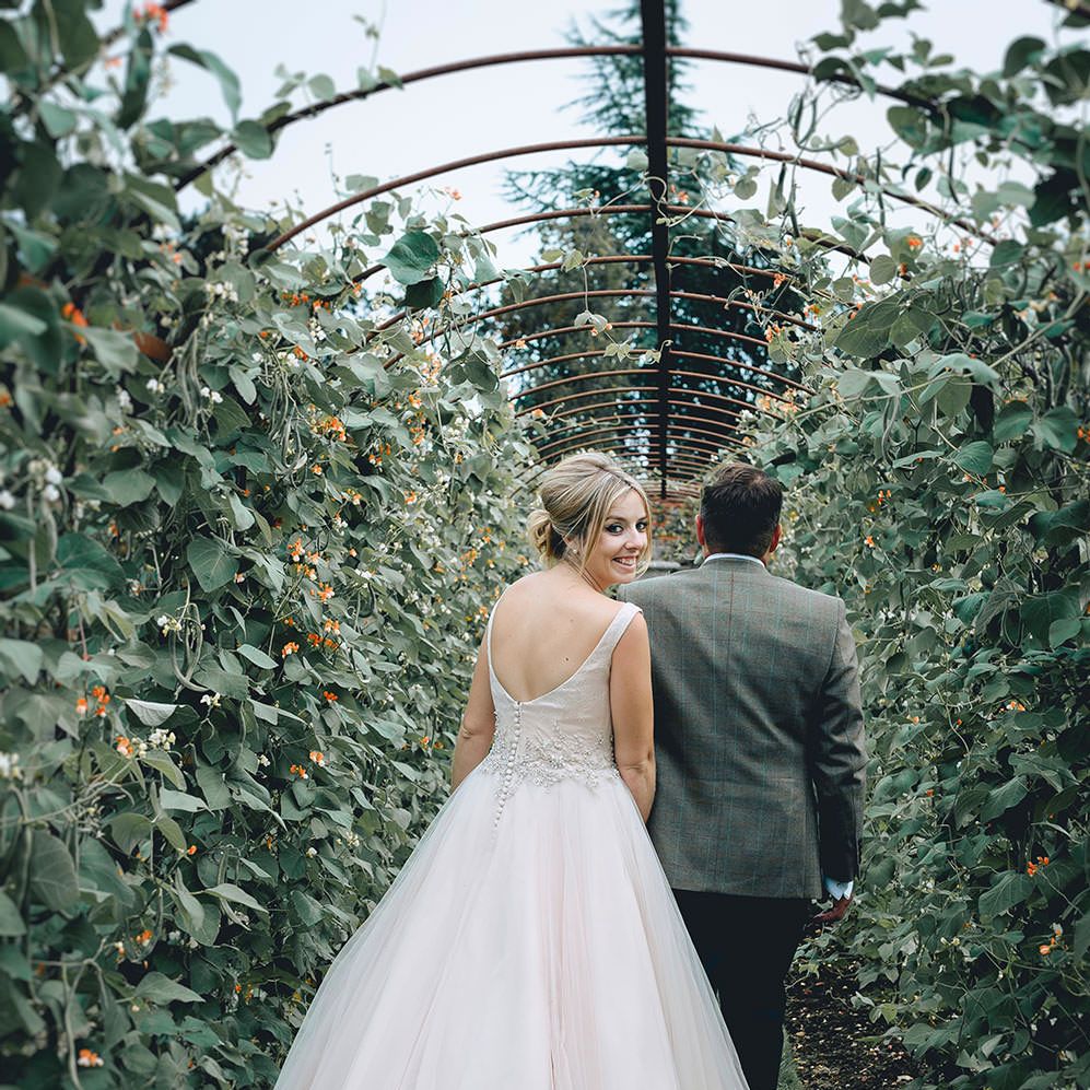 Bride in Phil Collins Bridal Gown & Groom in Chino's & Tweed Jacket at Helmingham Hall Gardens