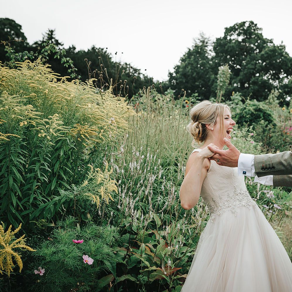 Bride in Phil Collins Bridal Gown & Groom in Chino's & Tweed Jacket at Helmingham Hall Gardens