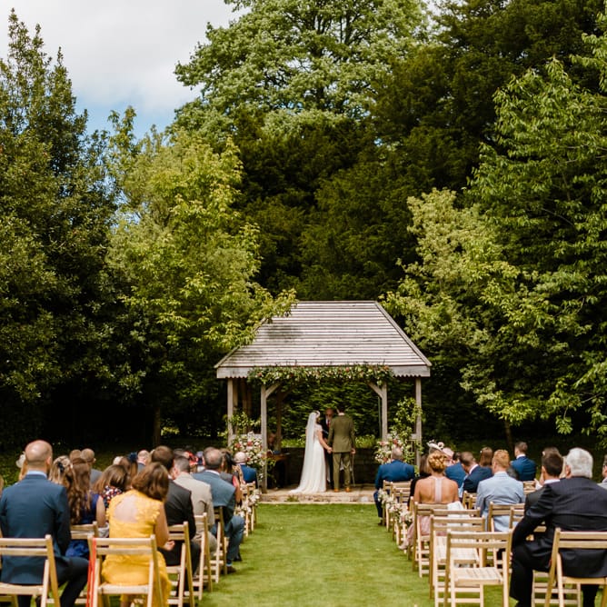 Wedding Ceremony | Bride in Jenny Packham Gown | Groom in Hugo Morris Tweed Suit | Outdoor Ceremony & Rustic Barn Reception at Pennard House Somerset | John Barwood Photography
