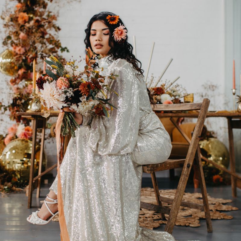Bride in silver sequin wedding dress holding an autumnal bouquet for 70s Disco theme