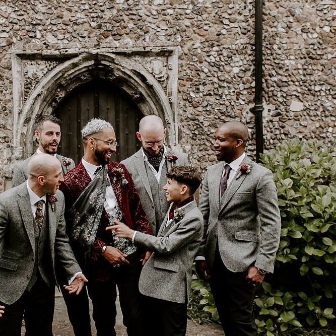Groom in pink blazer and groomsmen in grey waistcoats and jackets