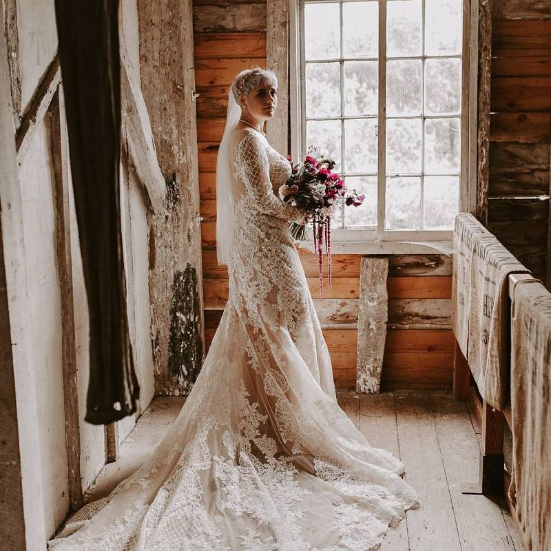 Bride in Lillian West wedding dress with illusion neckline and long sleeves