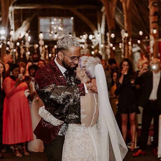Bride and groom first dance in a festoon lit barn with bride in Lillian West wedding dress