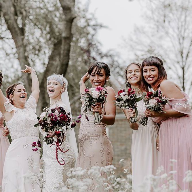 Fun bridal party portrait with bridesmaids in pink dresses and bride in Lillian West dress