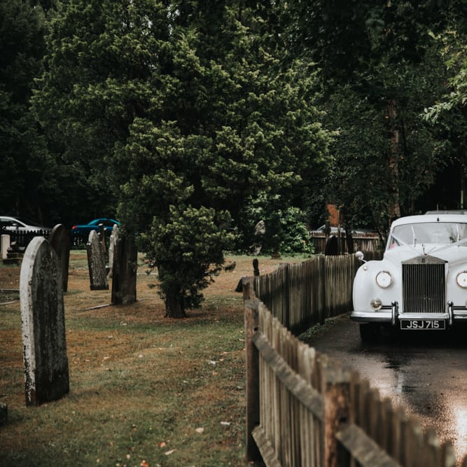 White vintage wedding car arriving at church ceremony