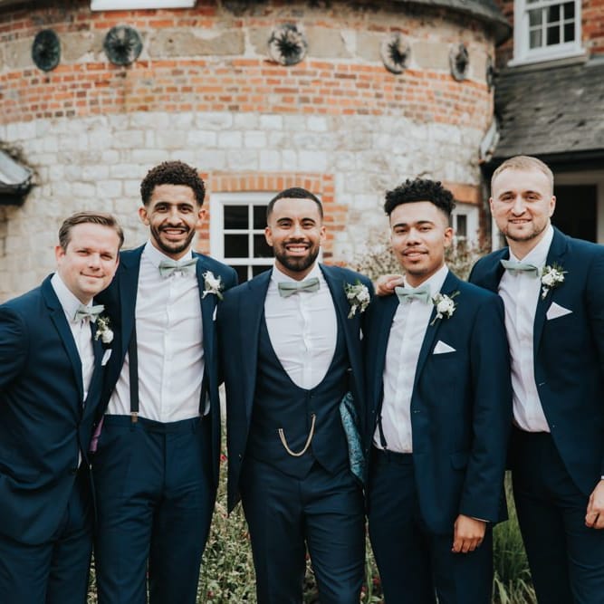Groom with groomsmen in matching blue wedding suits with bowties