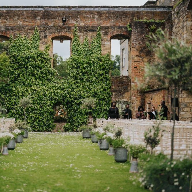 Outdoor wedding ceremony at Newburgh Priory with olive tree decor