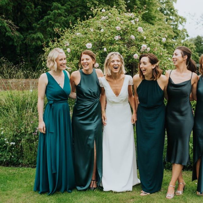 Bride and her bridesmaids in emerald green dresses for outdoor wedding ceremony