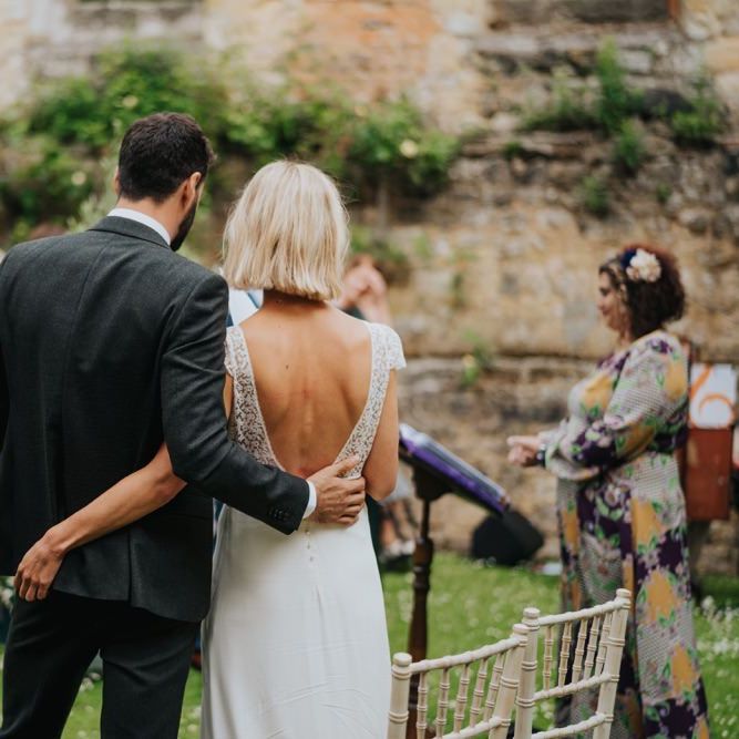 Bride and groom embrace at outdoor wedding ceremony with celebrant