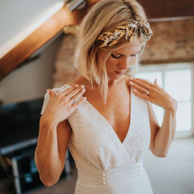 Bride wearing cap sleeve laced dress with pearl embellishment and a gold headband