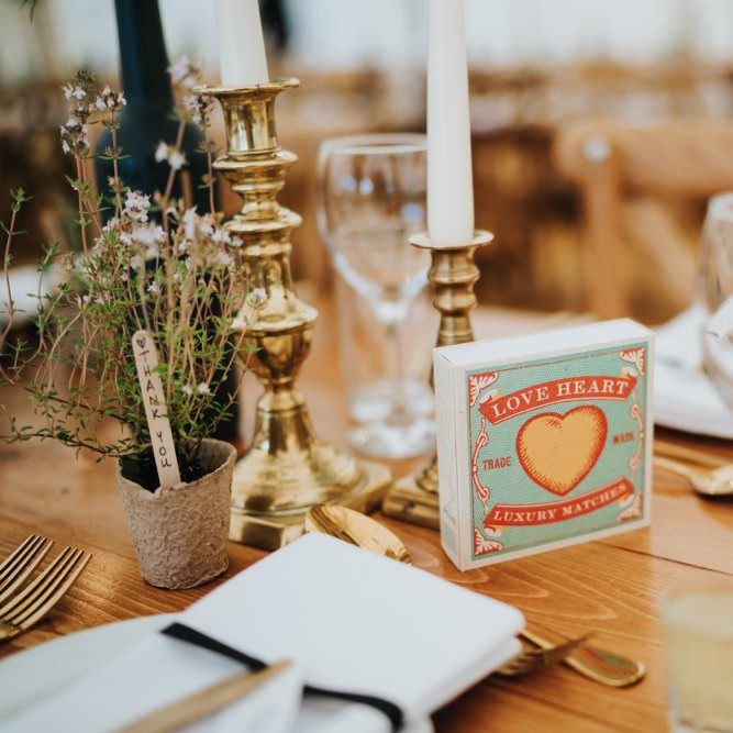 Gold candlesticks and painted wine bottle table numbers for marquee reception with rustic styling
