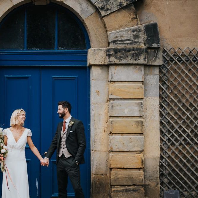 Bride wearing cap sleeve lace top dress and groom in three piece suit