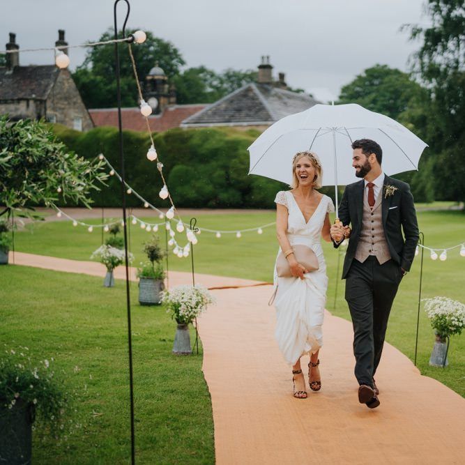 Bride and groom arrive at marquee reception with fairy lights