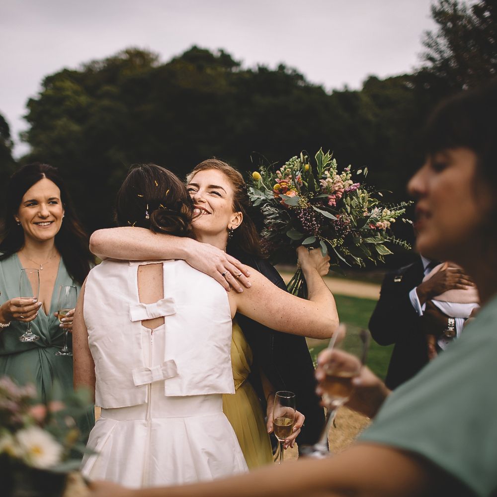 Bride in Homemade Wedding Dress with Bow Back Hugging Wedding Guests