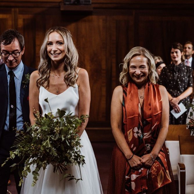 Bride walking down the aisle at Stoke Newington Town Hall wearing two piece gown and foliage bouquet
