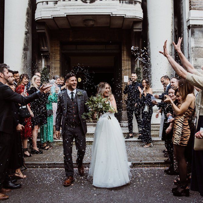 Confetti shot as couple exit Stoke Newington Town Hall with foliage bouquet