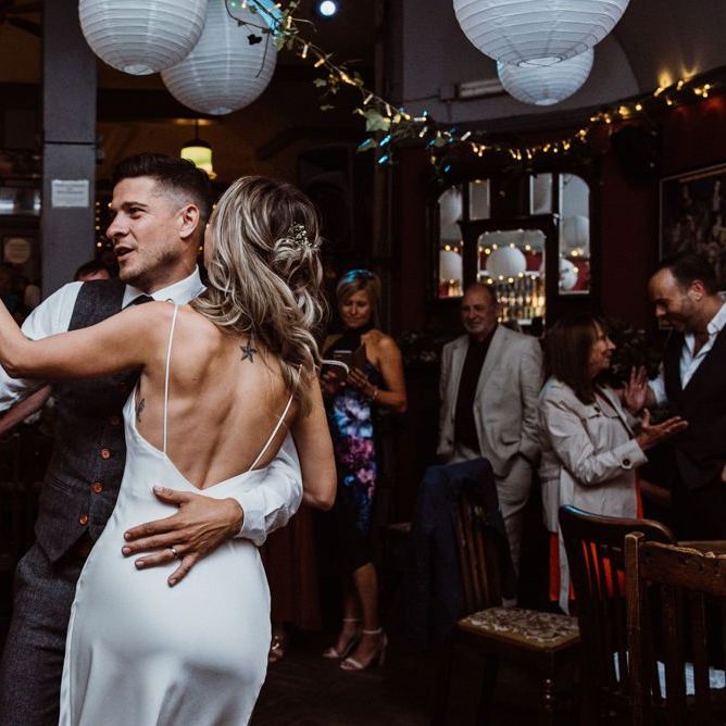 Bride and grooms first dance at pub reception with hanging foliage decor