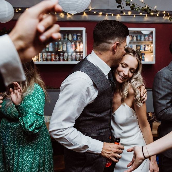 Bride and grooms first dance at pub reception with hanging foliage decor