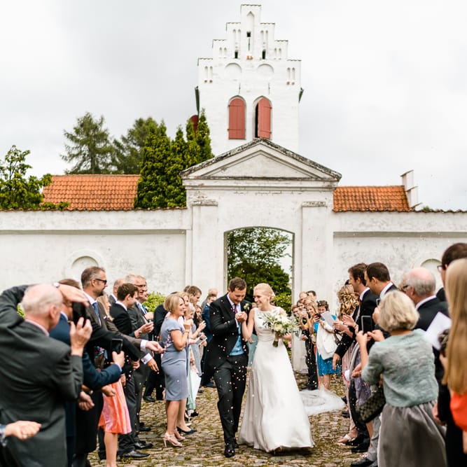 Confetti Exit | Bride in Caroline Castigliano Wedding Dress | Groom in Henry Herbert Tailors Morning Suit | Traditional Green/Blue Danish Wedding at Scandinavian Country House, Jomfruens Egede in Faxe, Denmark | John Barwood Photography