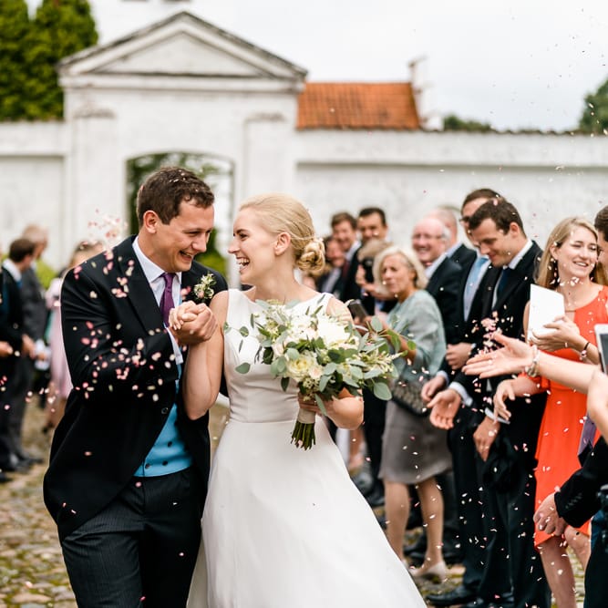 Confetti Exit | Bride in Caroline Castigliano Wedding Dress | Groom in Henry Herbert Tailors Morning Suit | Traditional Green/Blue Danish Wedding at Scandinavian Country House, Jomfruens Egede in Faxe, Denmark | John Barwood Photography