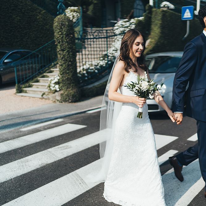 Bride in Grace Loves Lace Mia Wedding Dress and Groom in Taliare Navy Suit Walking Across a Zebra Crossing