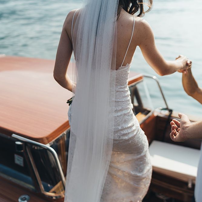 Bride in Grace loves Lace Mia Wedding Dress and Cathedral Length Veil Getting onto Boat on Lake Como