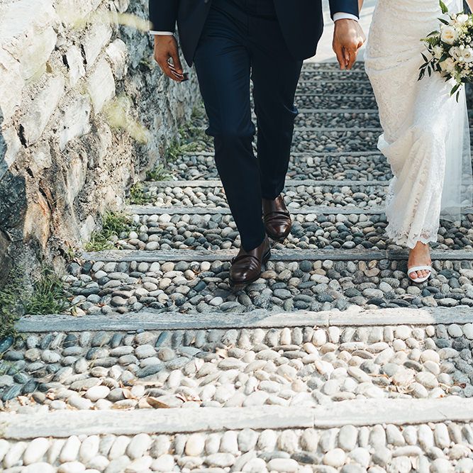 Groom in Navy Suit with Monk Strap Shoes and Bride in Lace Wedding Dress with Strappy Sandals