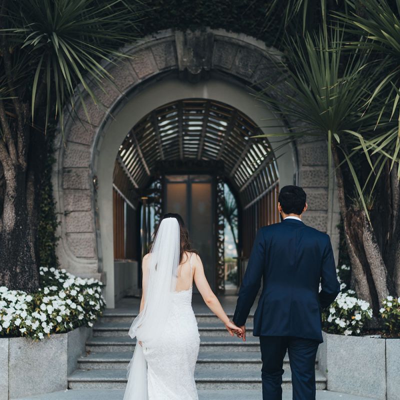 Bride in Grace Loves Lace Mia Wedding Dress and Groom in Taliare Navy Suit Going to Intimate Wedding Reception